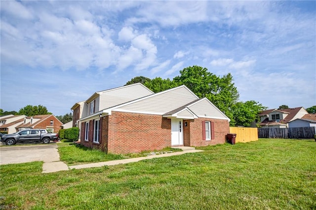 view of front of property with a front lawn, fence, and brick siding