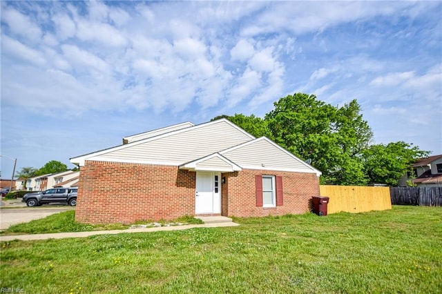 view of front facade with brick siding, fence, and a front lawn