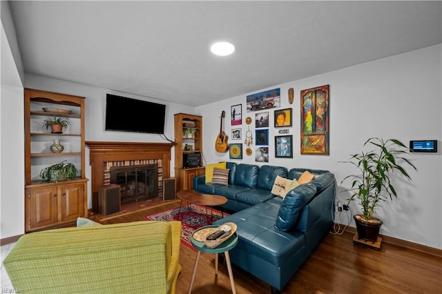 living area with baseboards, wood finished floors, and a fireplace