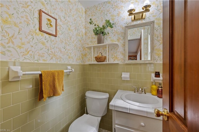 bathroom featuring wainscoting, wallpapered walls, vanity, and toilet