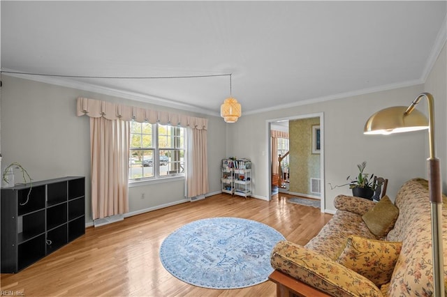 living area with baseboards, ornamental molding, wood finished floors, and visible vents