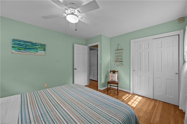 bedroom featuring baseboards, a ceiling fan, light wood finished floors, and a closet