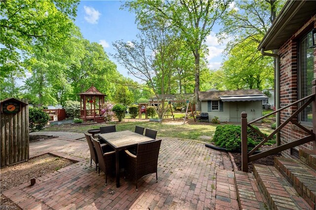 view of patio featuring outdoor dining area, an outbuilding, and a playground