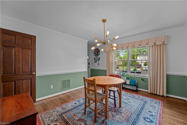 dining room featuring baseboards, wood finished floors, visible vents, and a chandelier