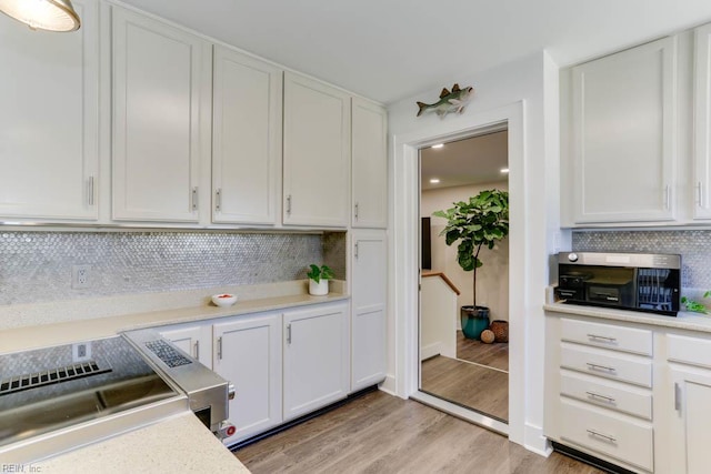 kitchen with light wood finished floors, decorative backsplash, light countertops, and white cabinetry