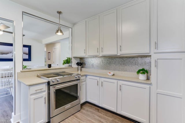 kitchen with light countertops, light wood-type flooring, stainless steel range with electric stovetop, and white cabinetry