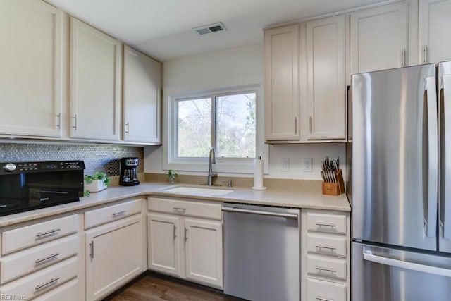 kitchen featuring stainless steel appliances, light countertops, backsplash, visible vents, and a sink