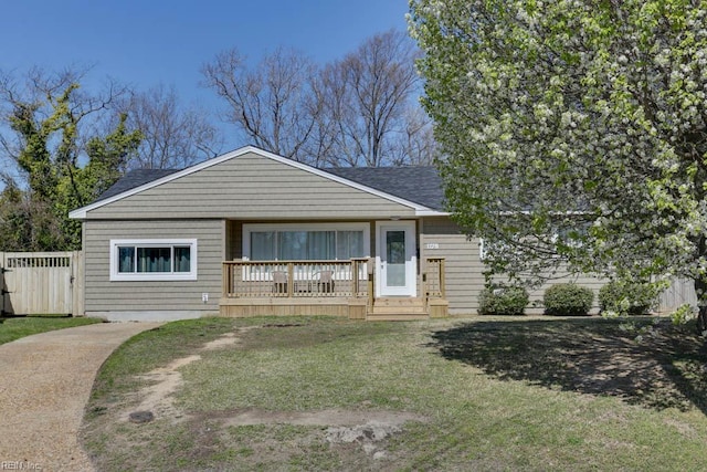 bungalow with fence, roof with shingles, covered porch, and a front yard