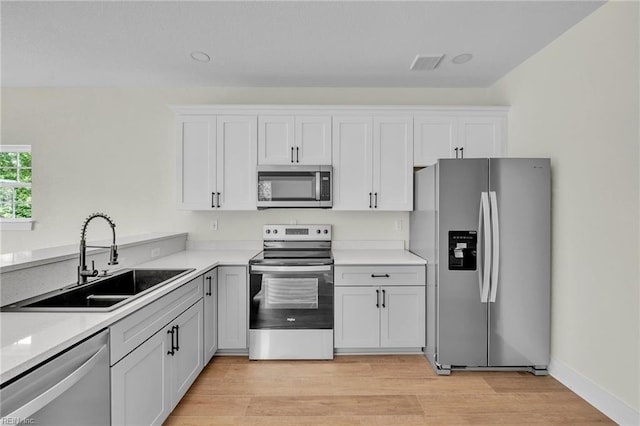 kitchen featuring light countertops, white cabinetry, stainless steel appliances, and a sink