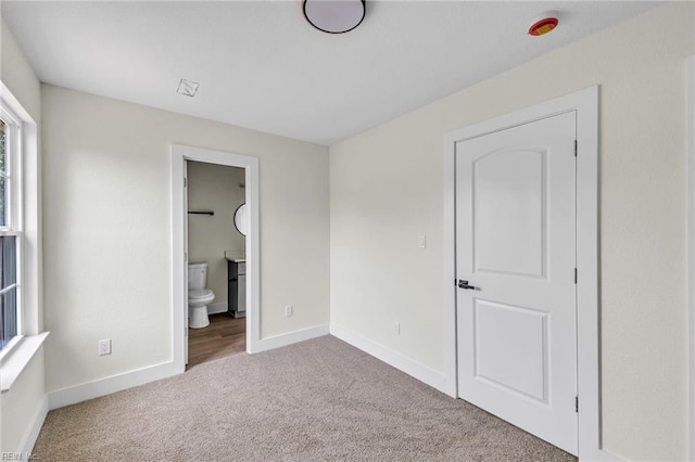 unfurnished bedroom featuring carpet floors, baseboards, and connected bathroom