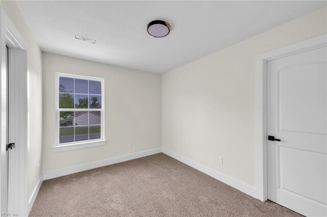 carpeted spare room featuring baseboards