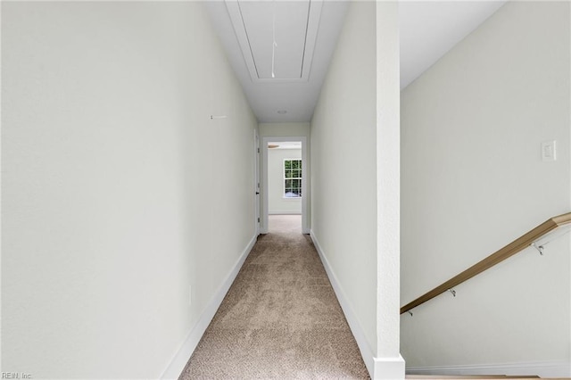 hall with attic access, light carpet, and baseboards
