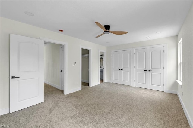 unfurnished bedroom featuring light carpet, baseboards, two closets, and ceiling fan