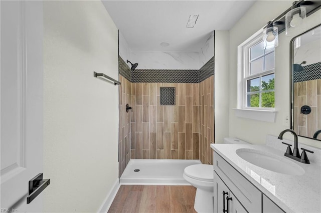 full bath featuring toilet, vanity, wood finished floors, and a stall shower
