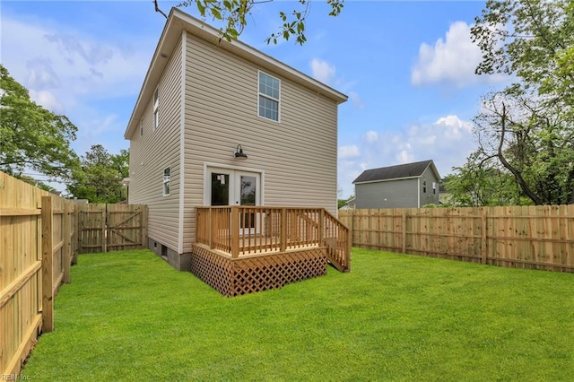 back of property with a lawn, a fenced backyard, french doors, and a deck