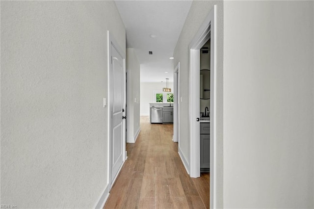 corridor featuring recessed lighting, light wood-style flooring, and baseboards