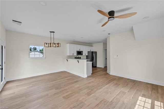 unfurnished living room with light wood finished floors, a ceiling fan, and baseboards