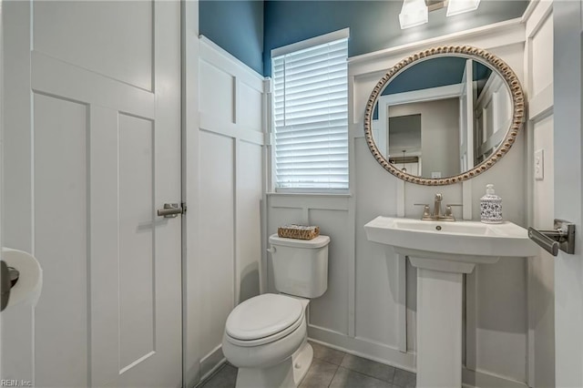 bathroom with a decorative wall, toilet, and tile patterned floors