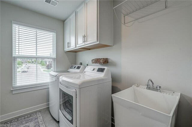 washroom featuring a sink, baseboards, visible vents, cabinet space, and washer and dryer