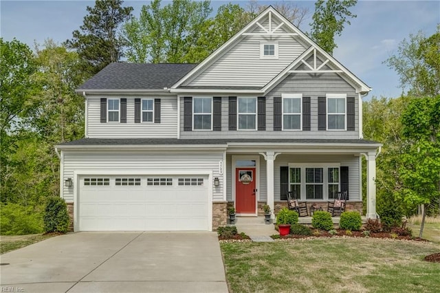 craftsman-style house with a front lawn, stone siding, concrete driveway, covered porch, and an attached garage