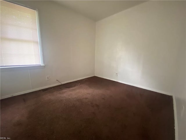 unfurnished room with vaulted ceiling, dark colored carpet, and baseboards