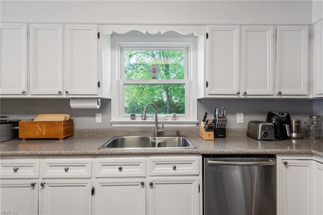 kitchen featuring stainless steel dishwasher, a sink, and white cabinetry