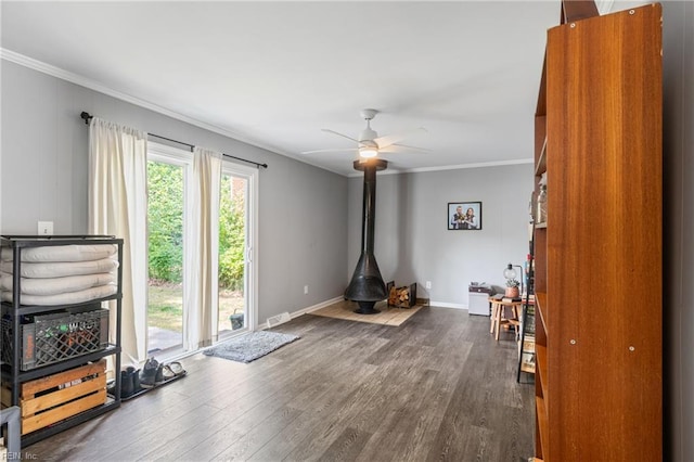 interior space featuring a wood stove, ornamental molding, and dark wood finished floors