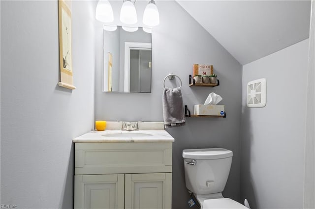 bathroom with vaulted ceiling, toilet, and vanity