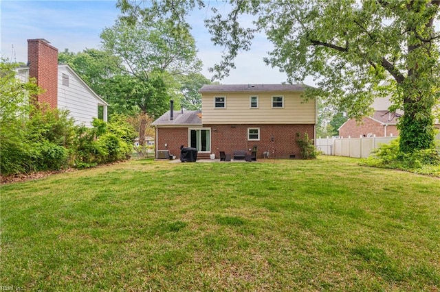 rear view of property featuring fence, a patio area, a lawn, and brick siding