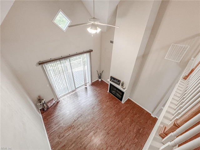 1004 Christiana Cir, Portsmouth, VA 23703 - unfurnished living room featuring a towering ceiling, wood finished floors, visible vents, a ceiling fan, and a glass covered fireplace