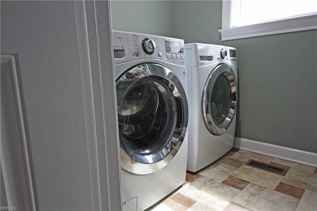 laundry area featuring washing machine and dryer, baseboards, stone finish floor, and laundry area
