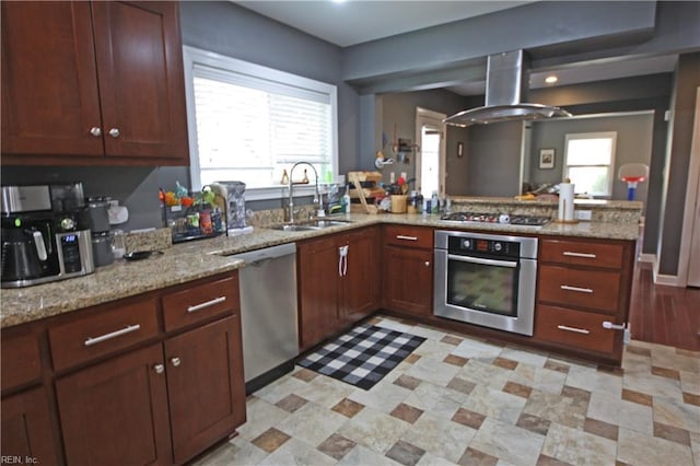 kitchen featuring a peninsula, a sink, a healthy amount of sunlight, extractor fan, and appliances with stainless steel finishes