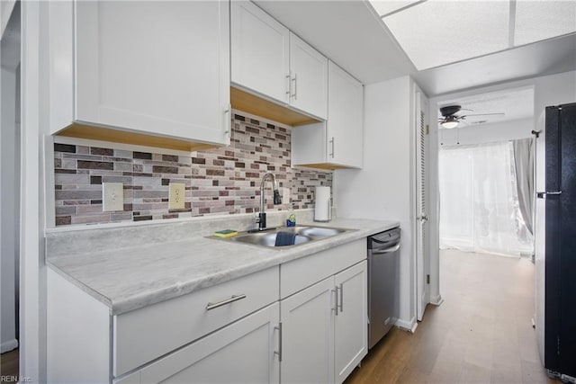 kitchen featuring white cabinets, a sink, light countertops, freestanding refrigerator, and dishwasher
