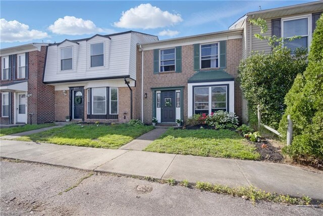 multi unit property with a front yard and brick siding