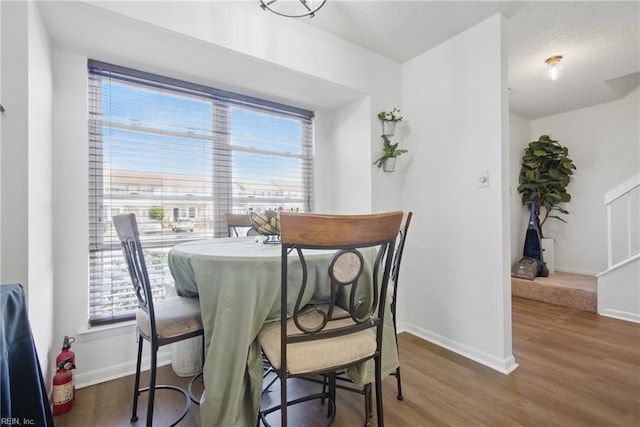 dining room with a textured ceiling, wood finished floors, and baseboards