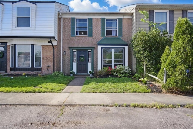 view of property featuring a front yard and brick siding