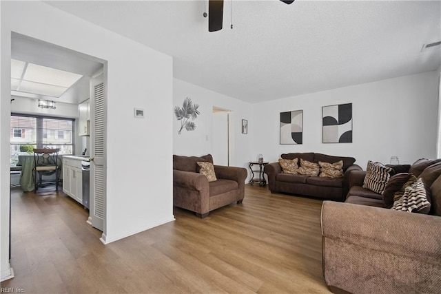 living area with visible vents, ceiling fan, baseboards, and light wood-type flooring