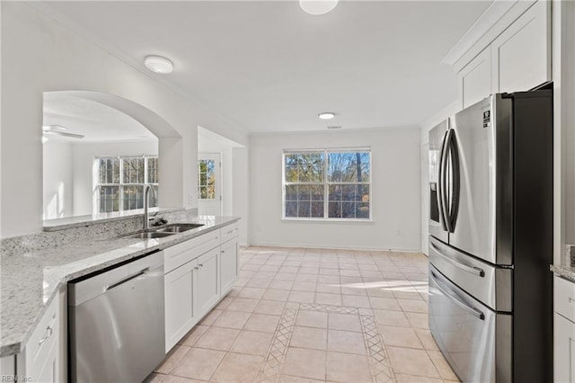 kitchen featuring appliances with stainless steel finishes, light tile patterned floors, white cabinetry, and a sink