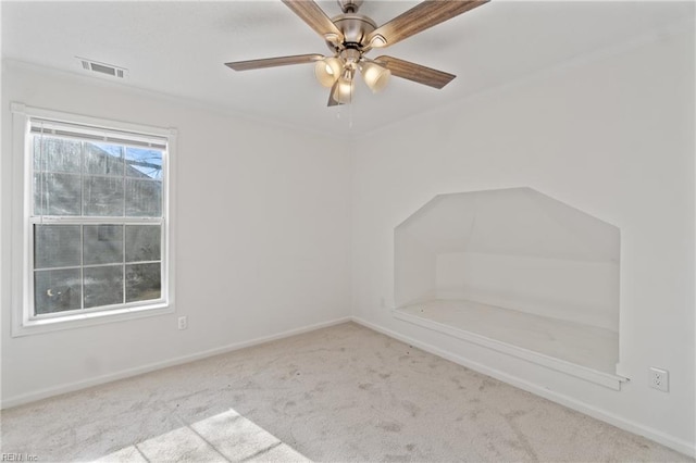 carpeted spare room with visible vents, baseboards, and ceiling fan