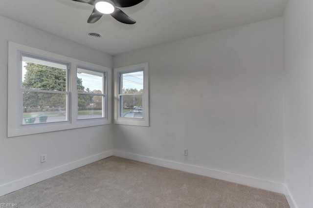 empty room with ceiling fan, visible vents, baseboards, and light carpet