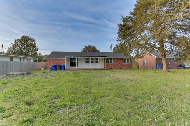 rear view of house with brick siding, a yard, and a fenced backyard