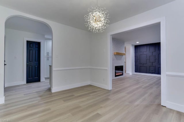 interior space featuring baseboards, arched walkways, wood finished floors, and a fireplace