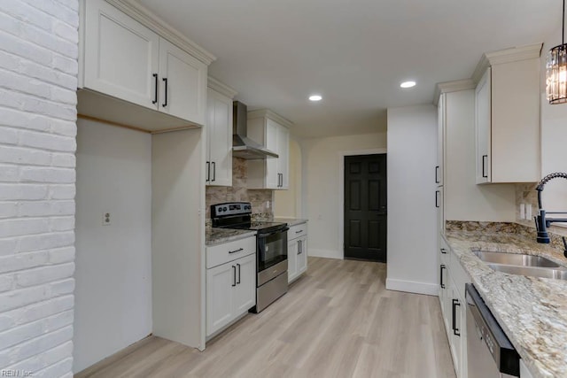 kitchen featuring light wood-style flooring, wall chimney exhaust hood, stainless steel appliances, and a sink
