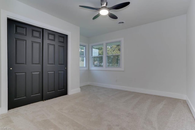 unfurnished bedroom with a closet, ceiling fan, carpet floors, baseboards, and visible vents