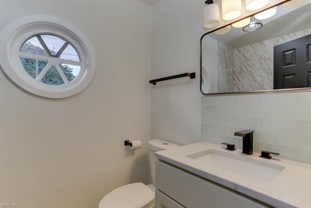 bathroom featuring toilet, vanity, and decorative backsplash