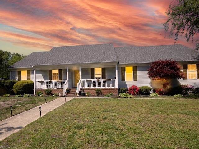view of front of house with a porch, a front yard, and a shingled roof