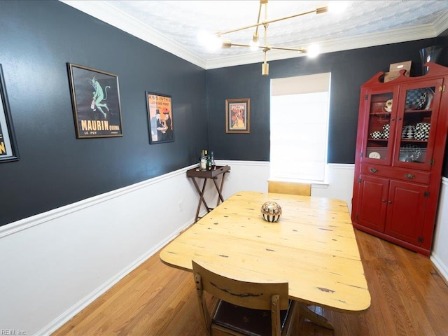 dining area featuring wainscoting, wood finished floors, and ornamental molding