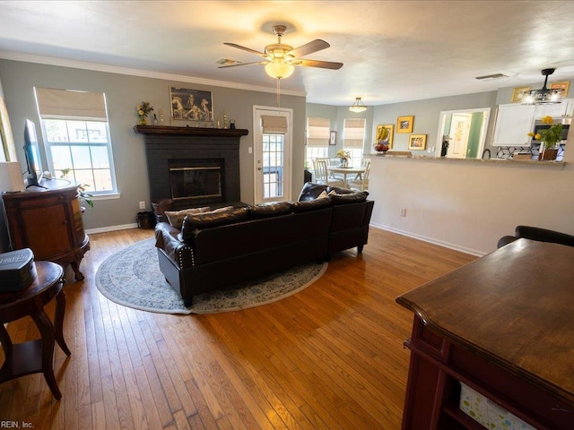 living area with baseboards, visible vents, ceiling fan, a fireplace, and wood-type flooring