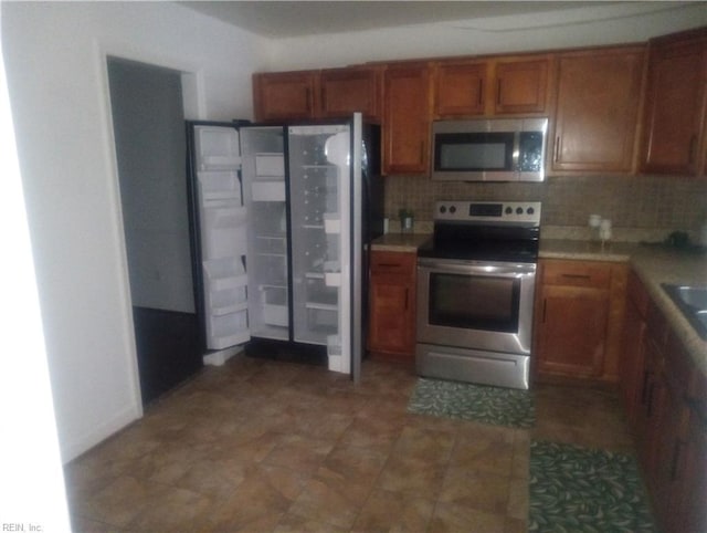 kitchen featuring tasteful backsplash, stainless steel appliances, light countertops, and brown cabinets