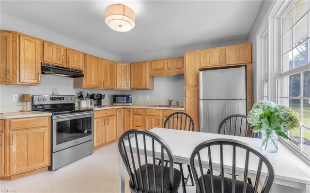 kitchen featuring light countertops, appliances with stainless steel finishes, under cabinet range hood, and a sink